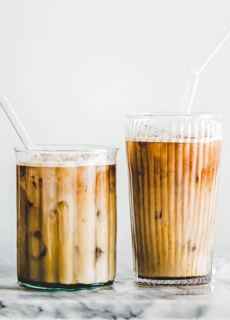 Homemade iced caramel macchiato coffee in glasses with straws on table