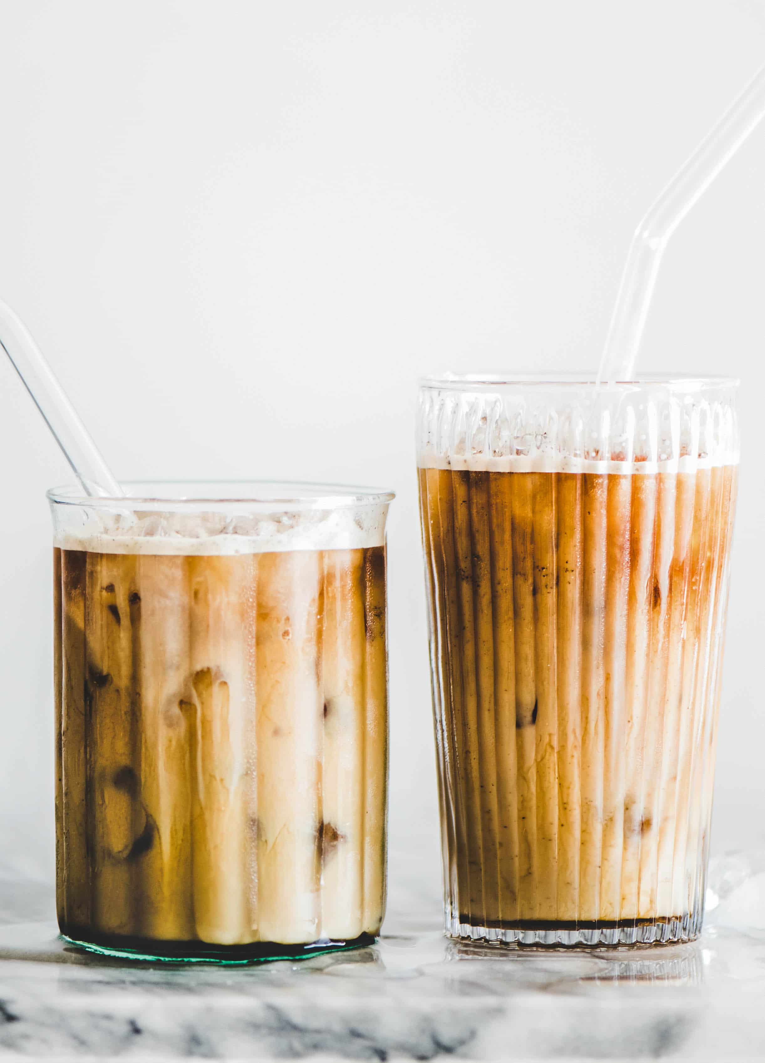 Homemade iced caramel macchiato coffee in glasses with straws on table