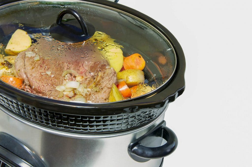 Close up slow cooker with roast beef and vegetables.