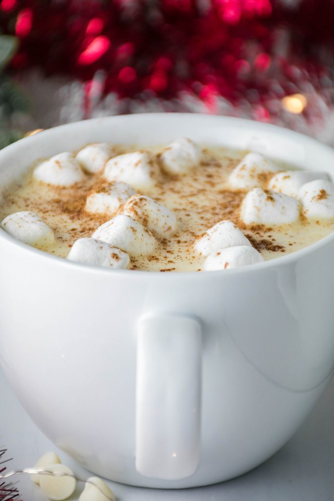 cup of white hot chocolate in front of christmas decorations
