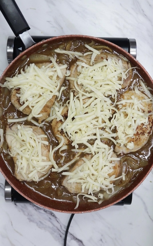 mozzarella cheese covered pork chops in a skillet