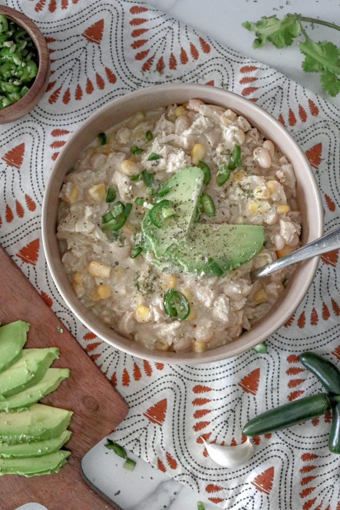 overhead of bowl of white chicken chili with avocados