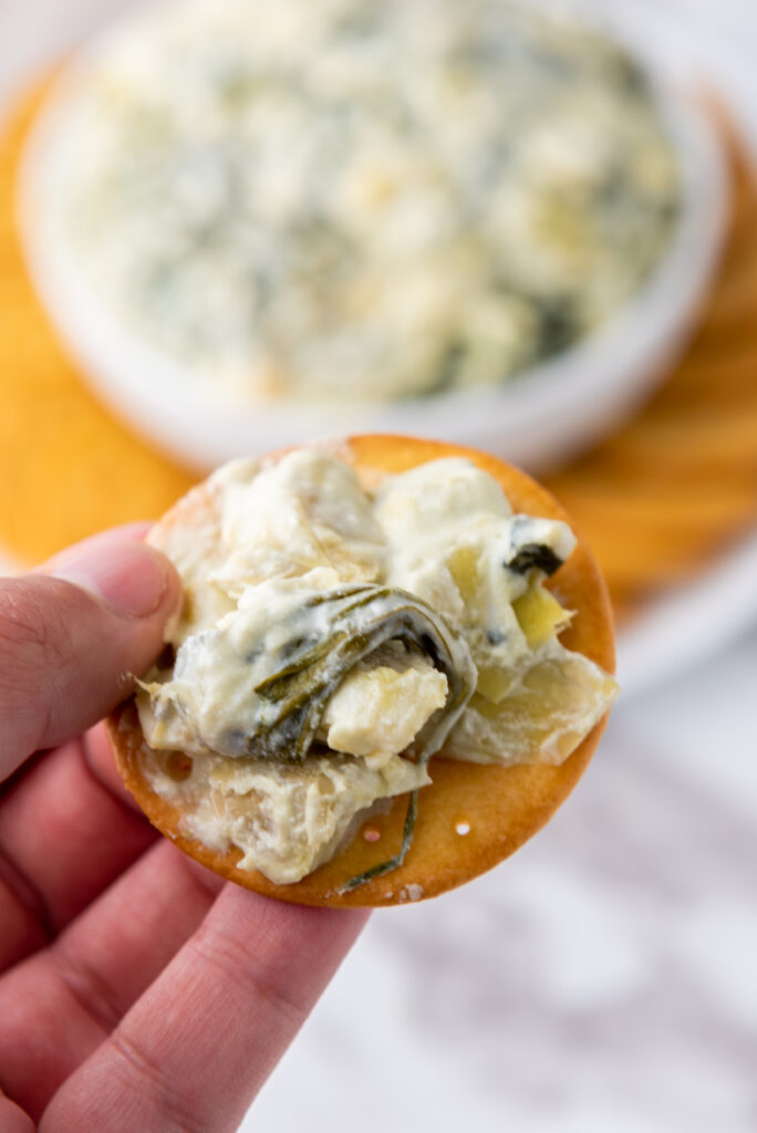 close up of slow cooker spinach dip on a cracker after cooking