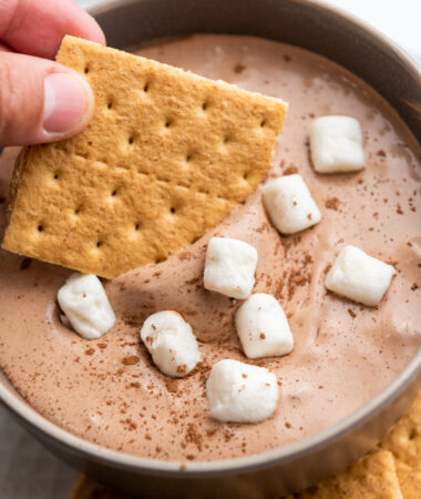 scooping hot cocoa dip onto a graham cracker